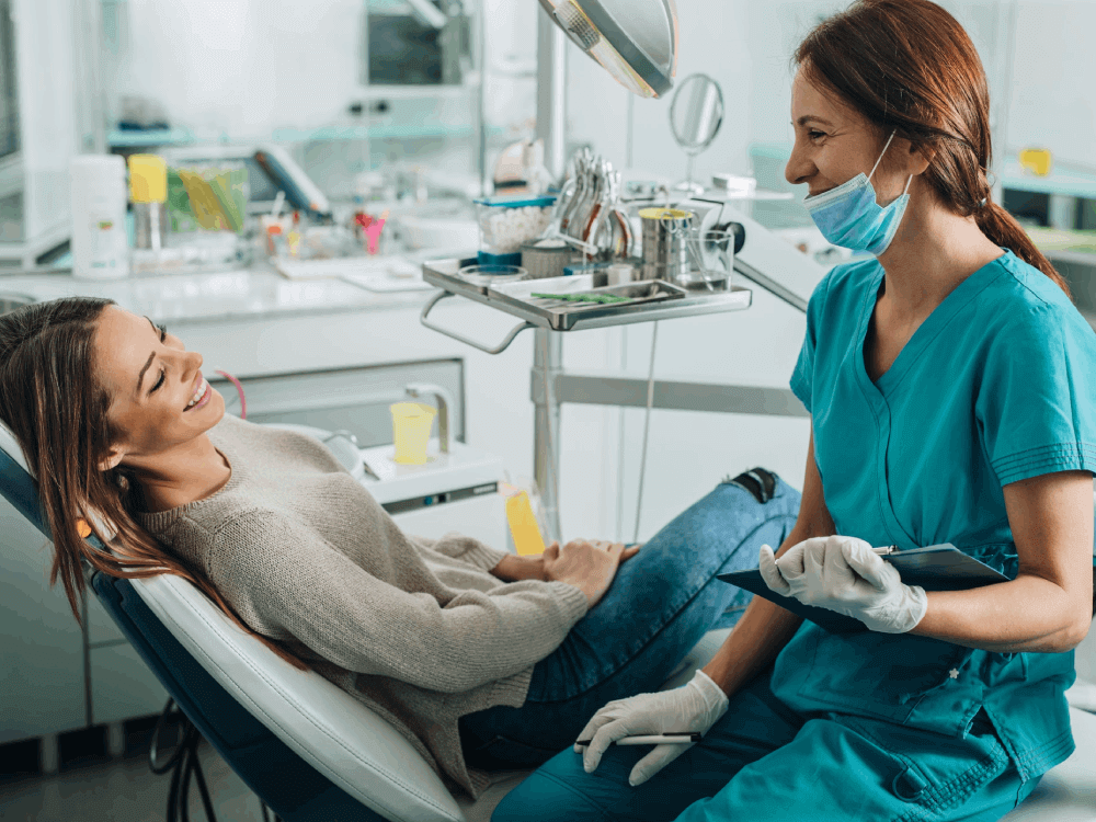 Smiling woman talking with dental assistant