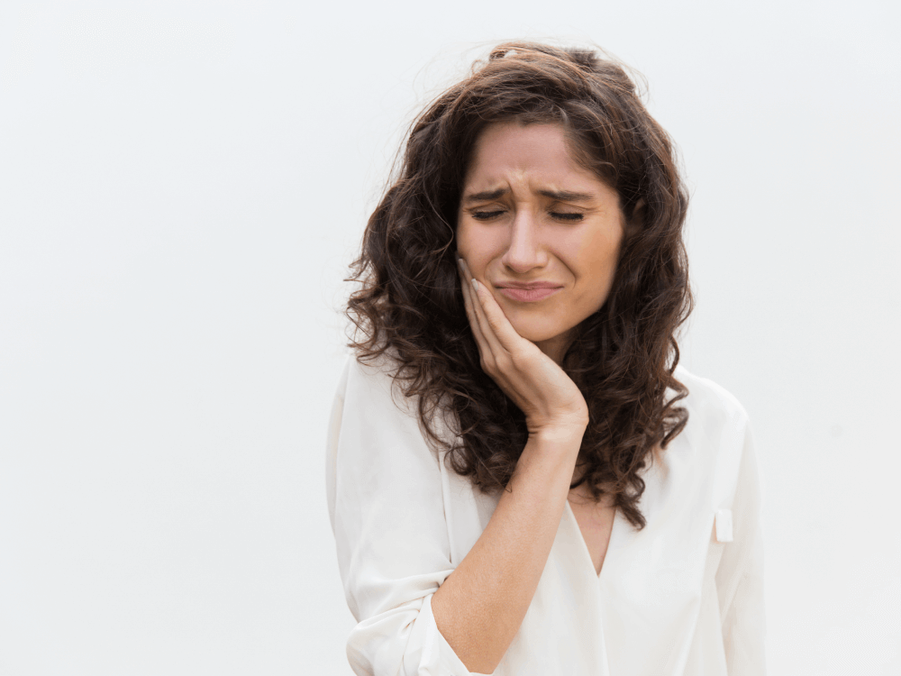 Woman in pain with a toothache holding jaw
